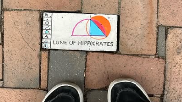 Picture of vans in front of a brick painted with the words LUNE OF HIPPOCRATES, artist unknown.